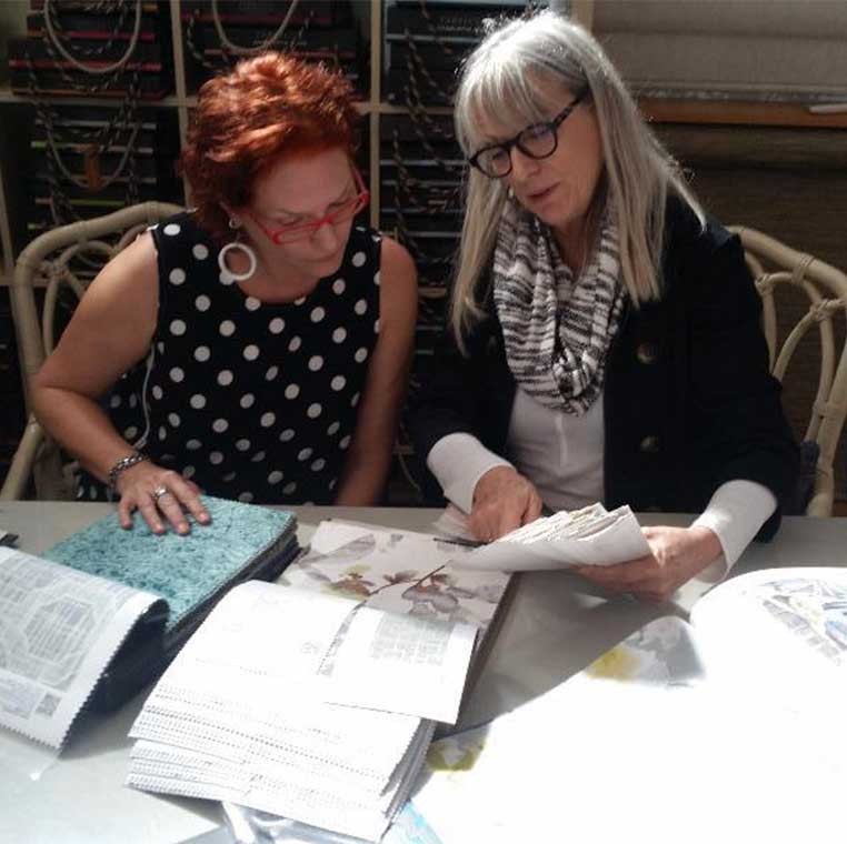 Two women at a table, looking at fabric samples